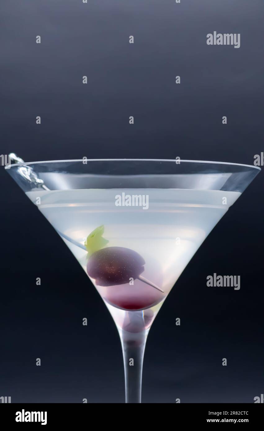 Sip of Luxury: Martini with Cherry Garnish Embodies Sophisticated Indulgence with flamingo pick on side of glass isolated on black background Stock Photo