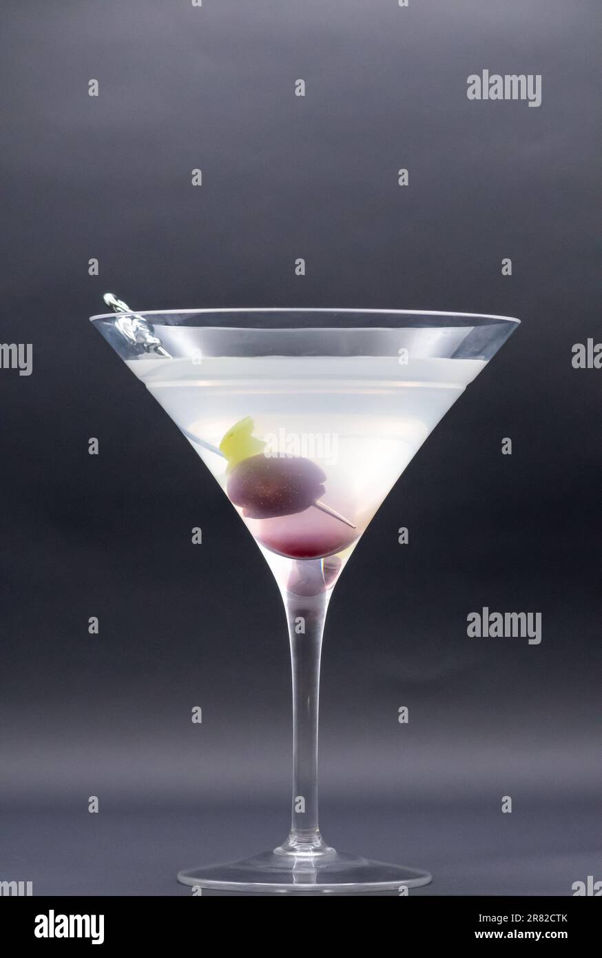 Tempting Twist: Martini with Luscious Cherry Garnish Steals the Show with flamingo pick on side of glass isolated on black background Stock Photo