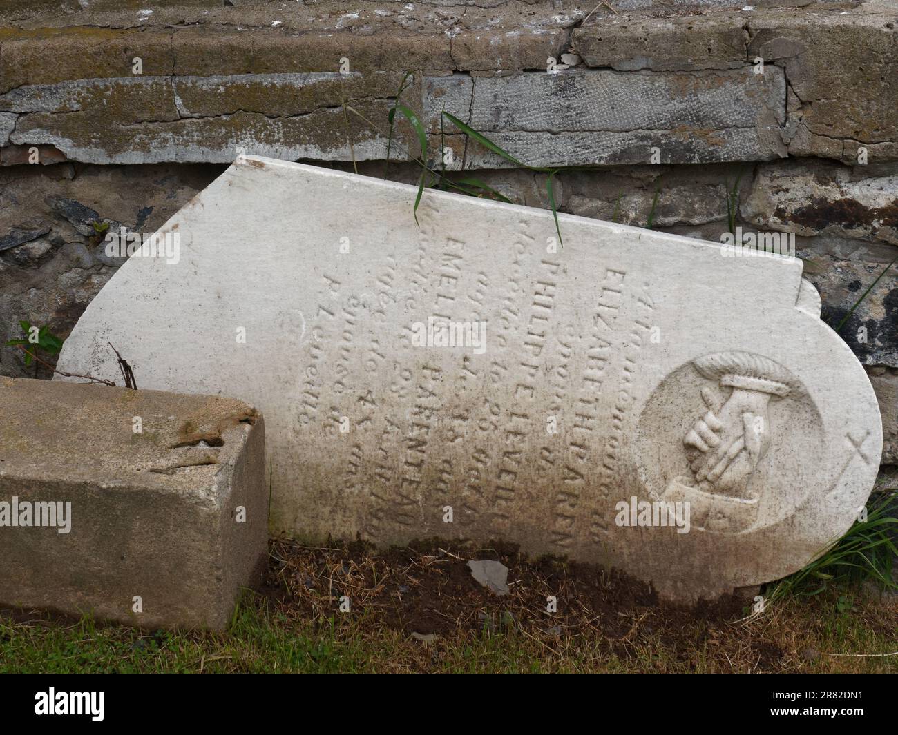 Old broken tombstone resting at the back of the Saint-Michel Catholic Church in Yamaska, Quebec, Canada Stock Photo