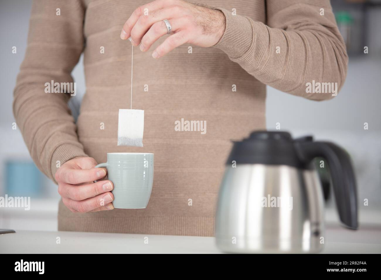 hands soaking tea bag on mug Stock Photo