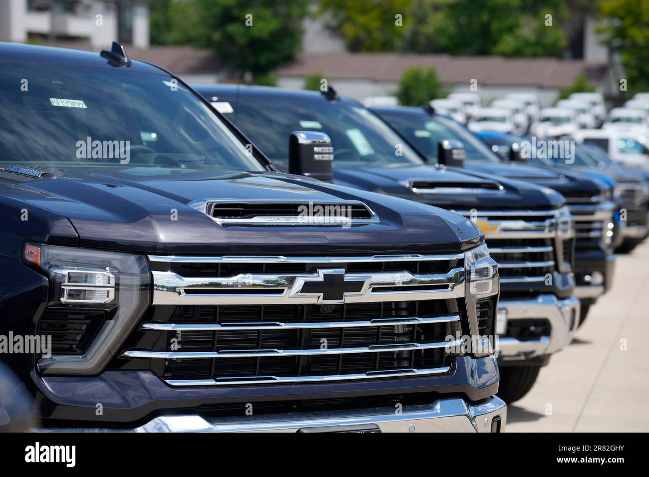 Unsold 2023 Silverado pickup trucks sit in a long row at a Chevrolet dealership Sunday, June 18