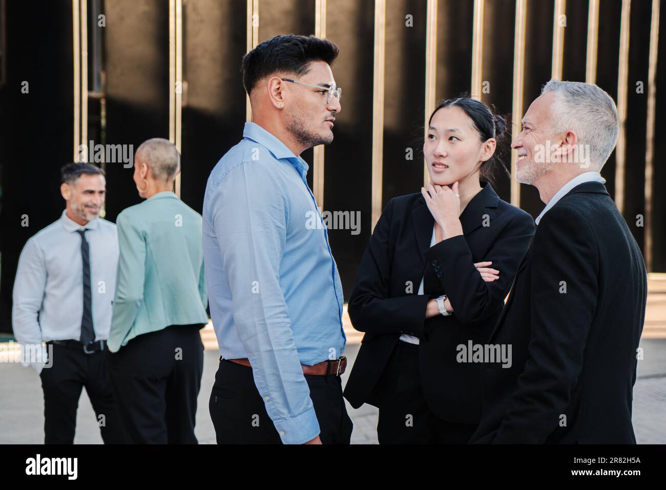 Finance businessmen and business woman wearing a formalwear suit, dicussing about new startup projects before starting the briefing. Group of lobby people talking, standing at the office workplace. High quality photo Stock Photo