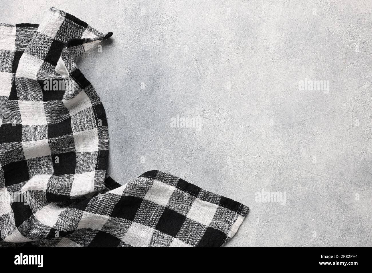 Black checkered tablecloth on light gray textured table, top view. Space for text Stock Photo