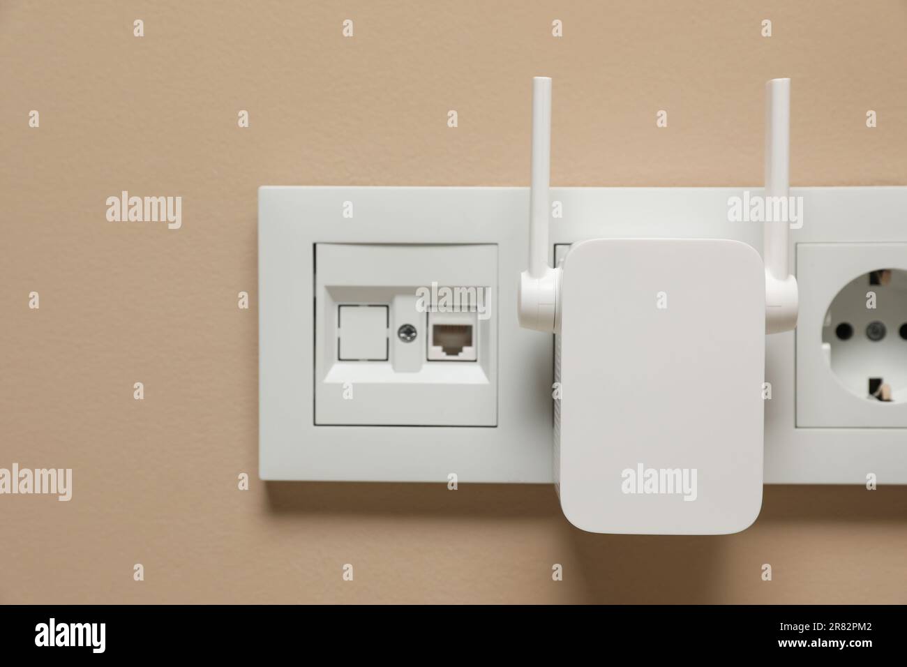 Wireless Wi-Fi repeater in power socket on beige wall Stock Photo - Alamy