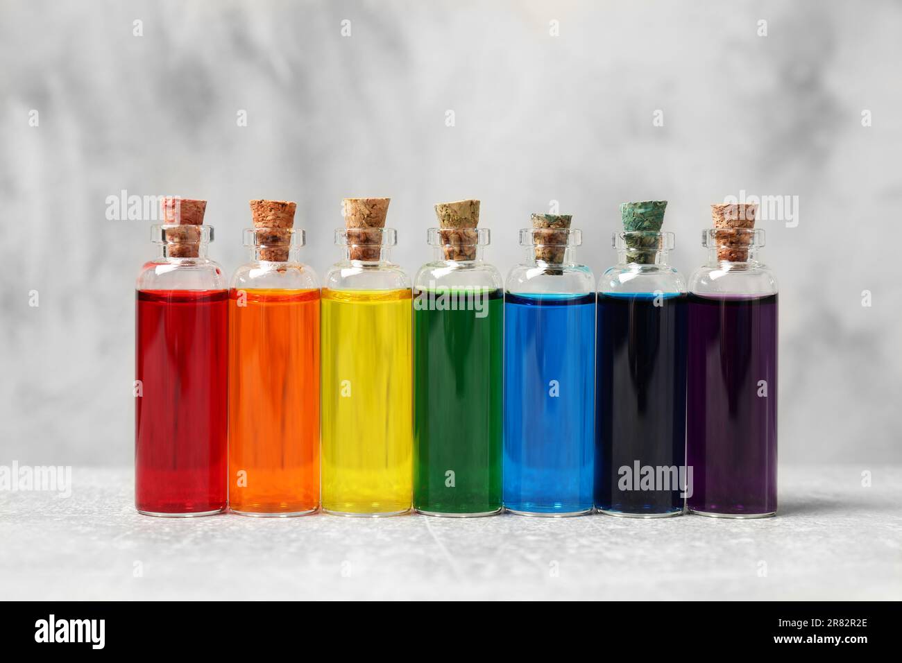 Glass bottles with different food coloring on white table Stock Photo