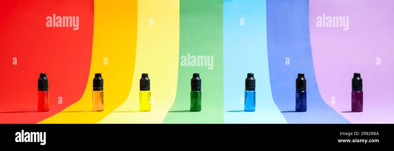 Bottles with different food coloring on rainbow background Stock Photo