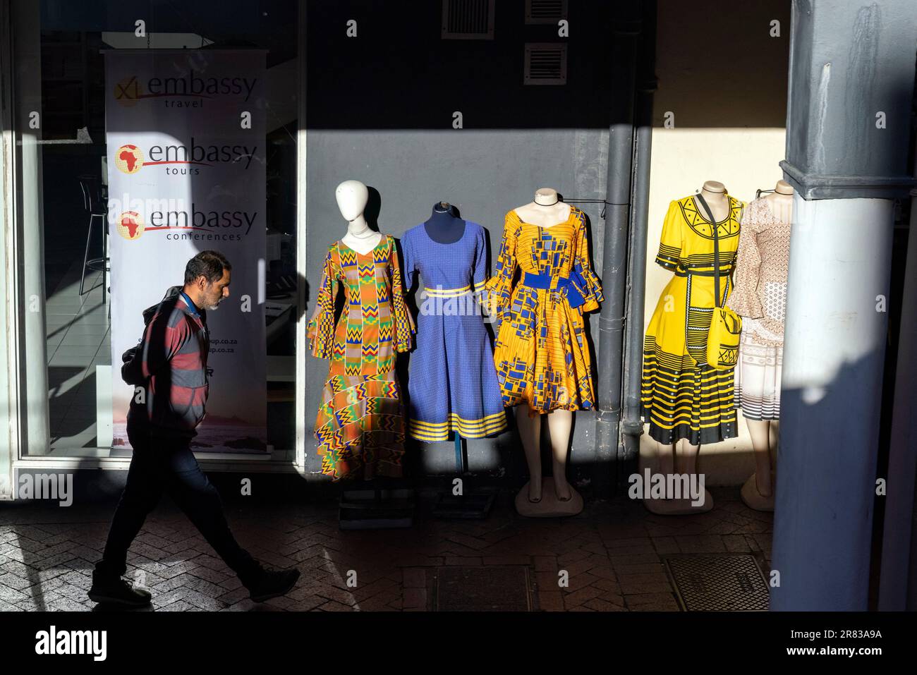 Street scene of man walking by colorfully dressed mannequins Cape