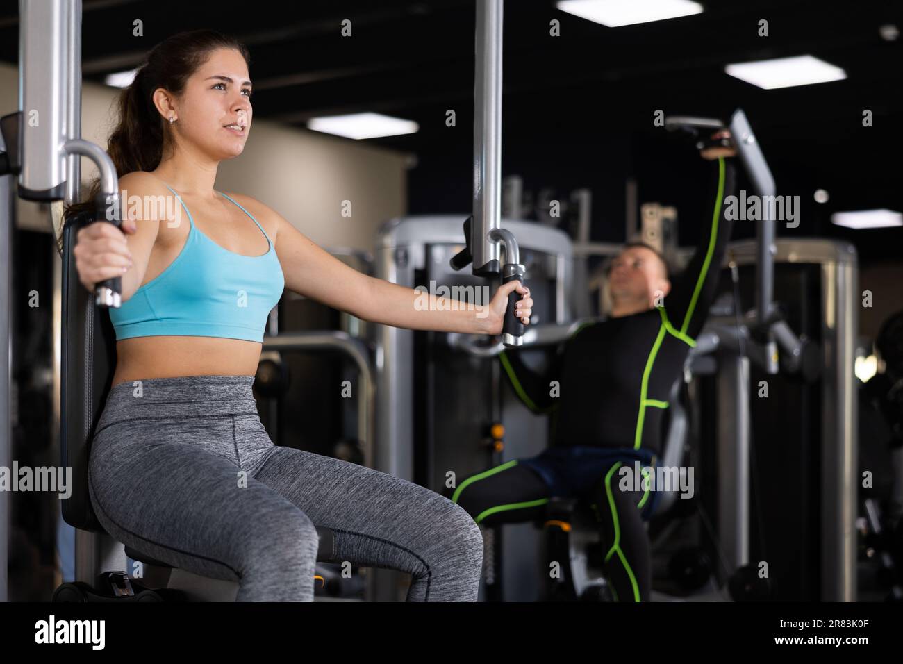 Girl performing butterfly exercise for chest in pec deck machine