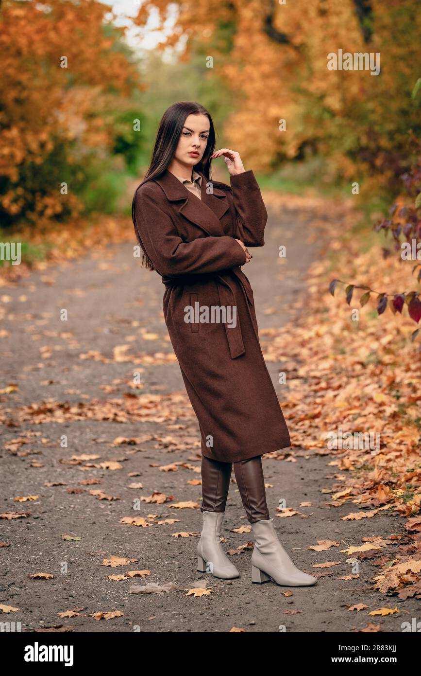 Young beautiful woman in long coat on the country lane in autumn Stock Photo