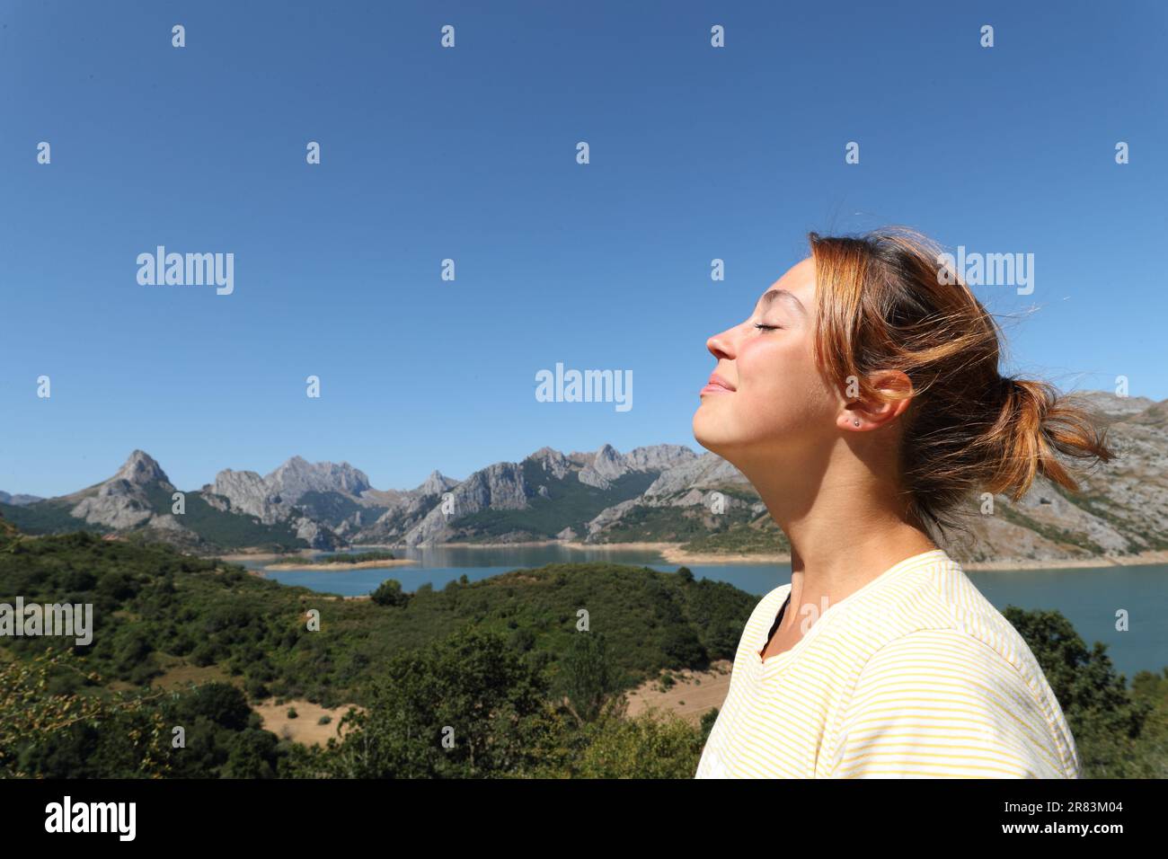Side view portrait of a happy woman breathing fresh air in the mountain Stock Photo