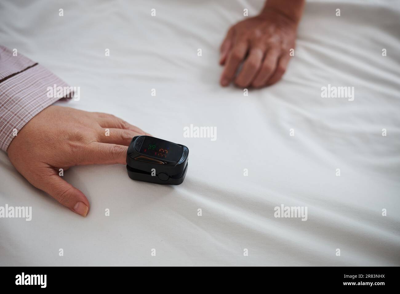 Senior woman with oximeter on finger checking oxygen level in her blood Stock Photo