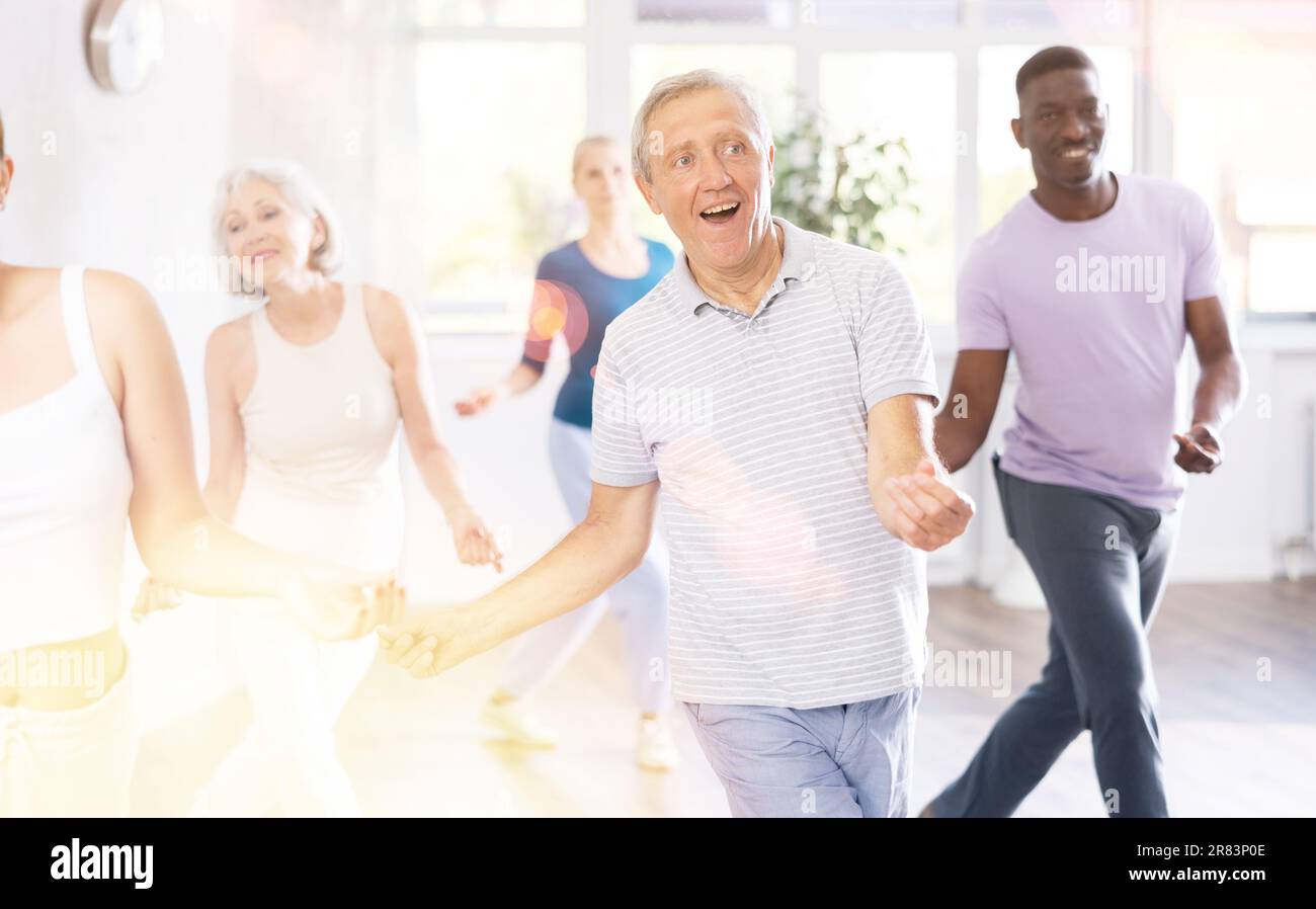 Elderly man learning dynamic dances during group class Stock Photo