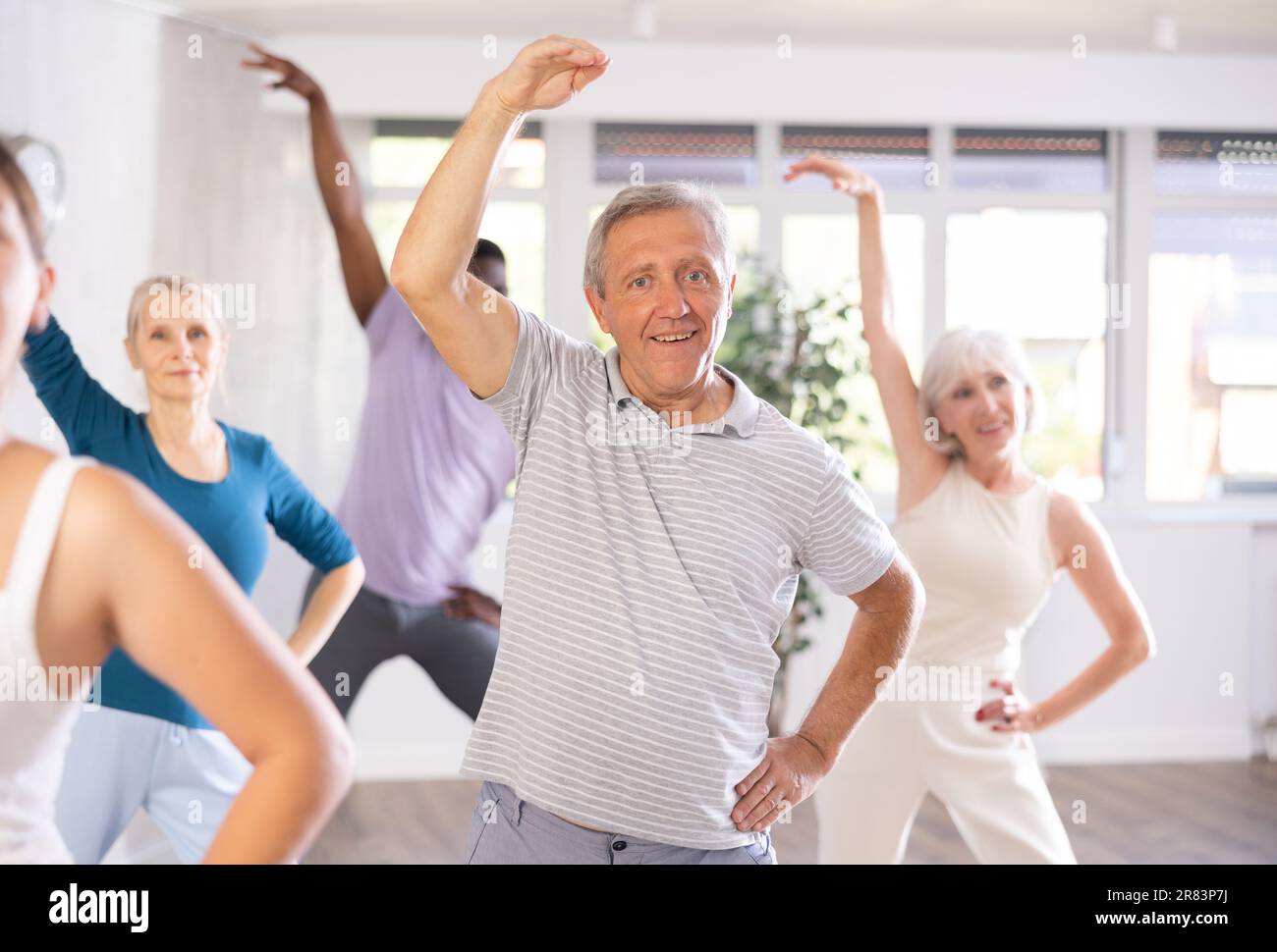 Elderly man learning dynamic dances during group class Stock Photo