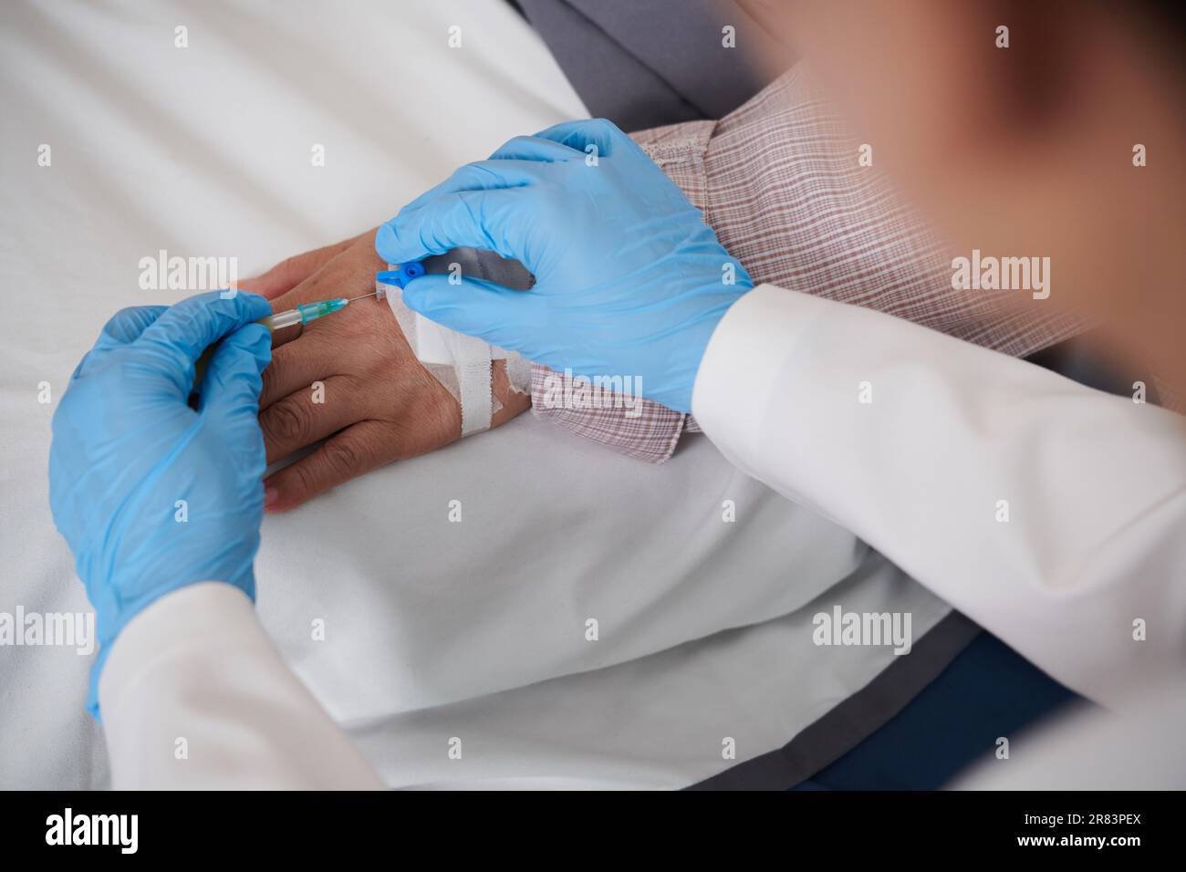 Closeup image of doctor inserting intravenous catheter in hand of