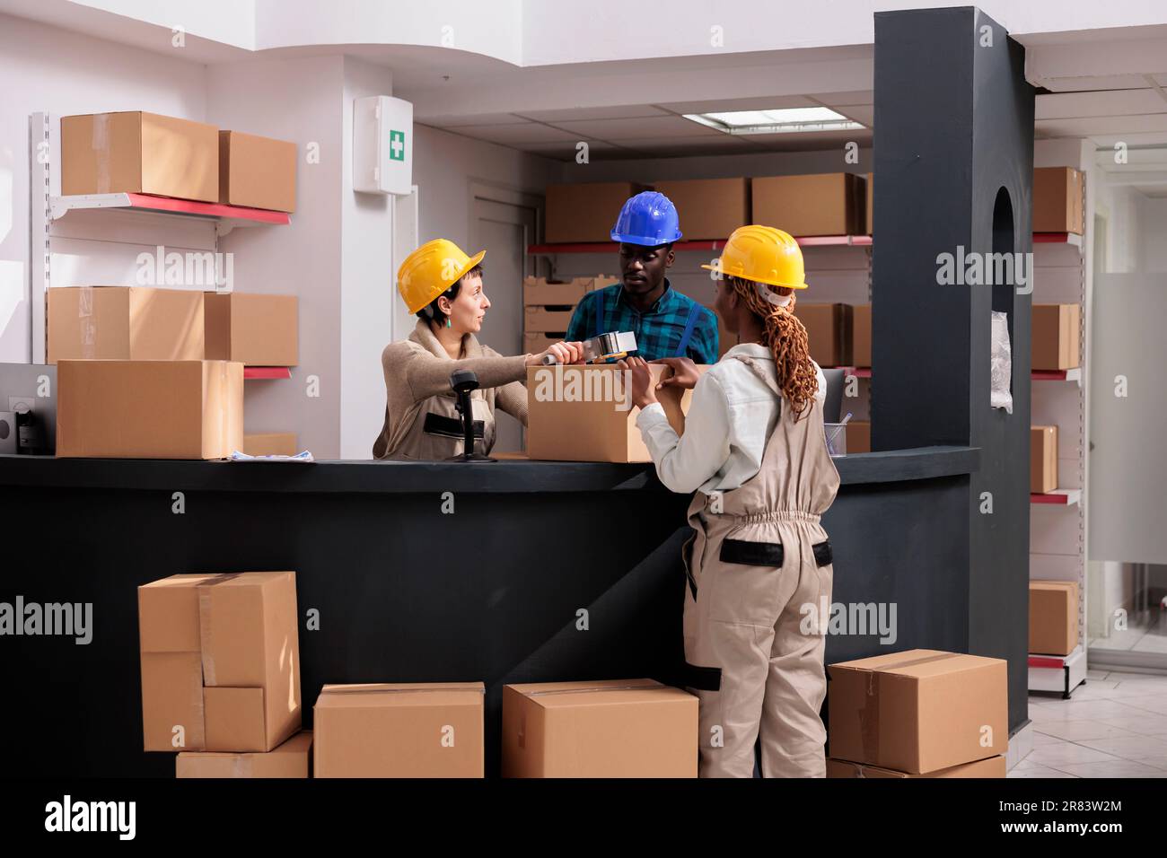 Warehouse workers team closing cardboard box with sticky tape dispenser