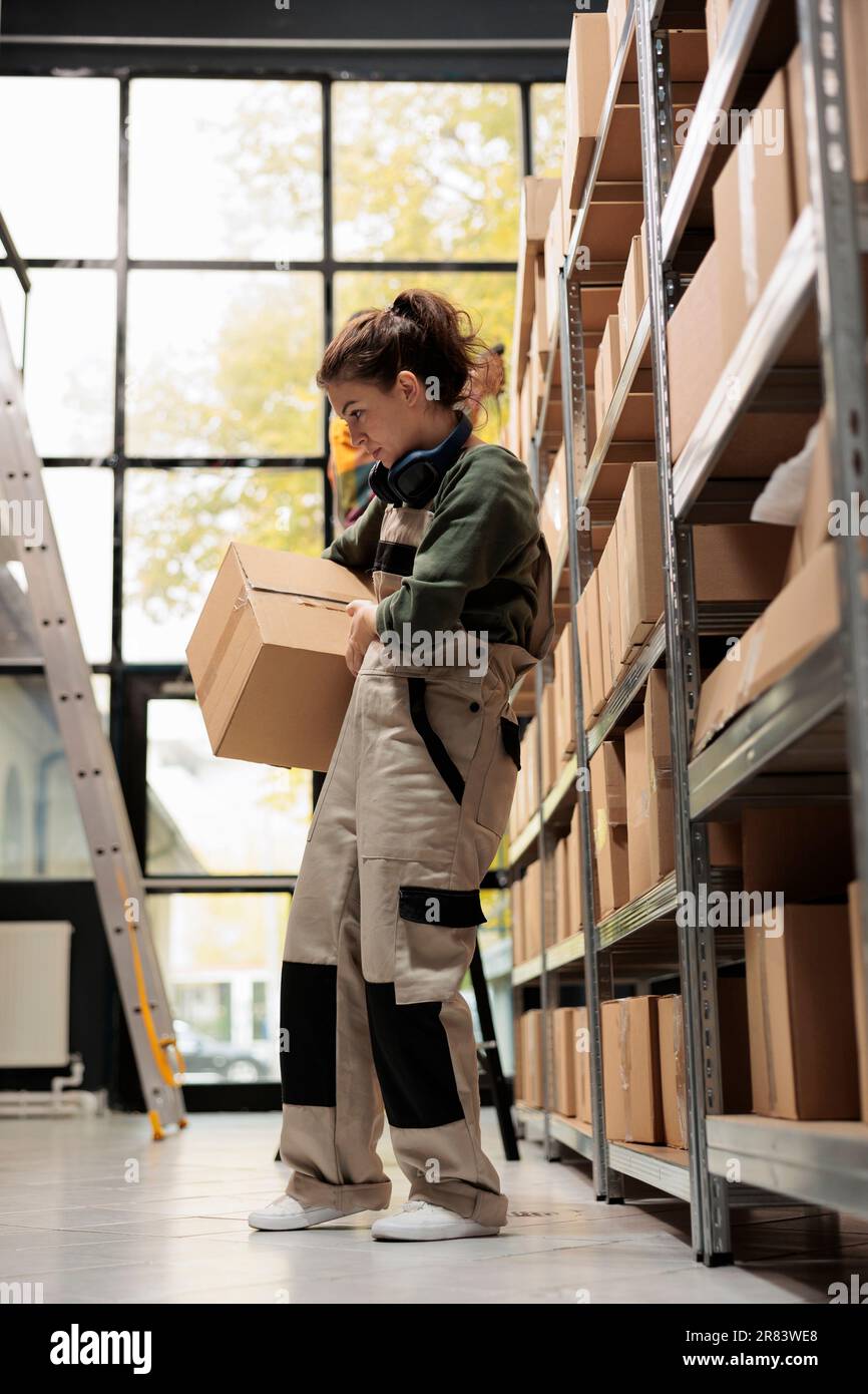 Small business employee working in storage room, carrying cardboard