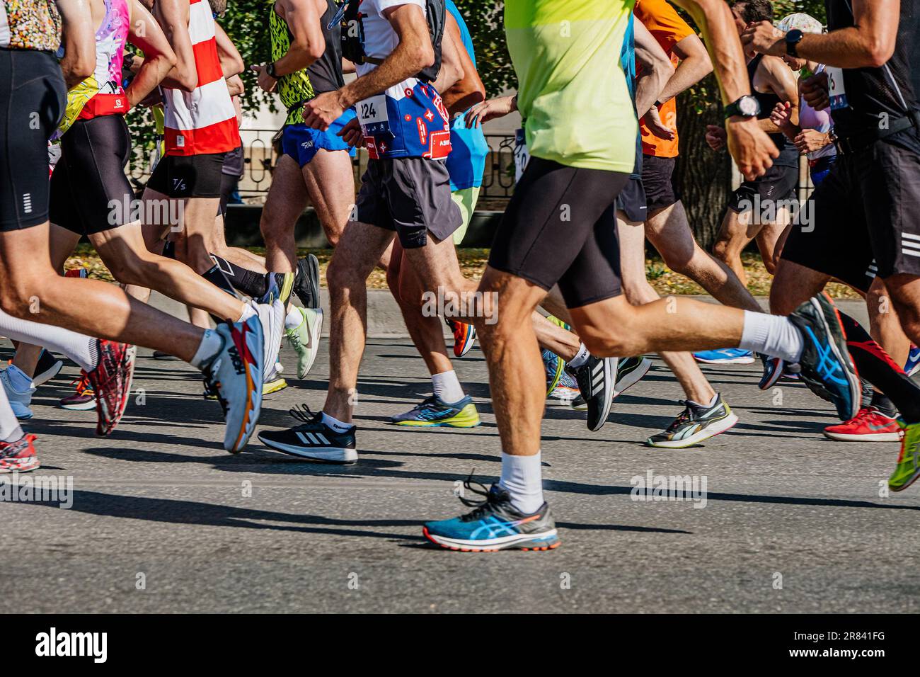 large group runners run city marathon race, legs male athletes in running  shoes Asics, Adidas, Hoka, Nike Stock Photo - Alamy