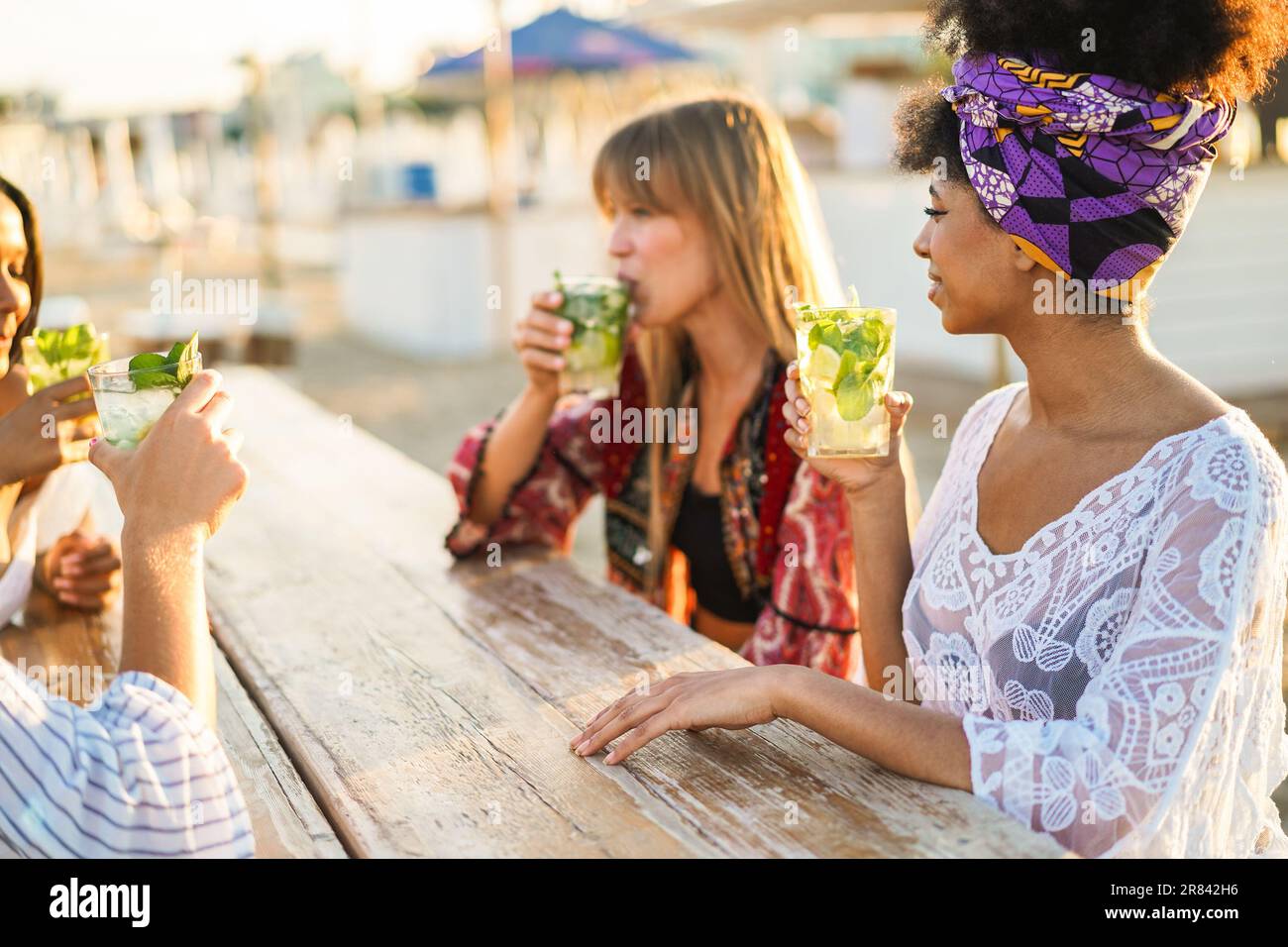 Multiracial happy friends having fun drinking mojitos at beach party - Focus on african girl right hand Stock Photo