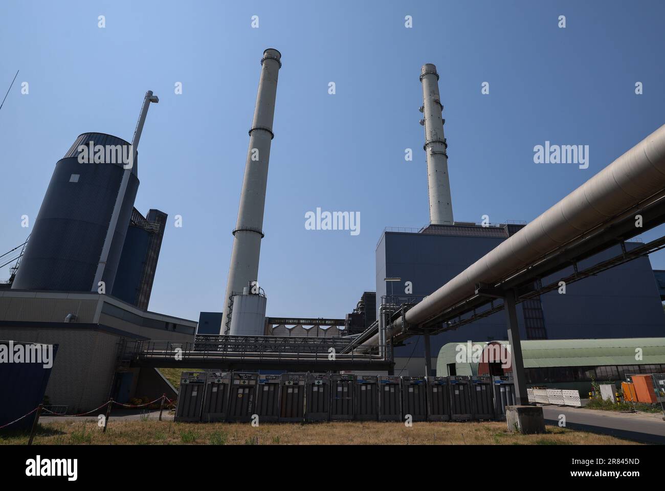 Wedel, Germany. 08th June, 2023. Chimneys and a district heating pipeline  (r) of the Wedel combined heat and power plant. The Wedel coal-fired power  plant is to be shut down in 2025