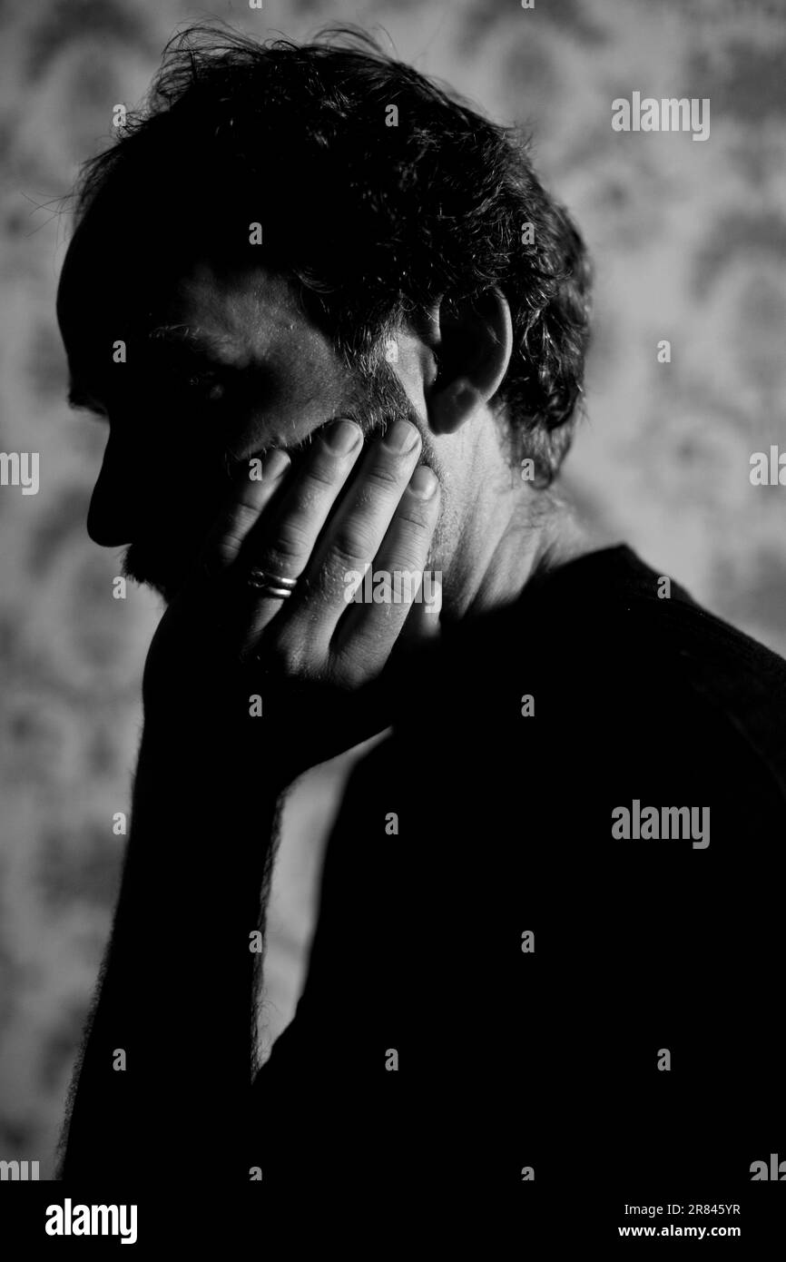 Man holding his head in front of decorative wallpaper stock photo alamy