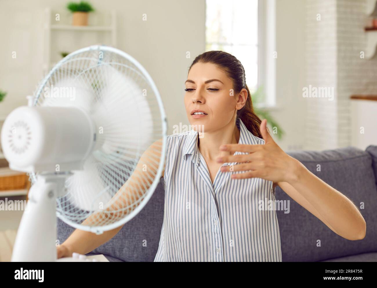 Woman, tired of hot summer weather, enjoying cold air blowing in her