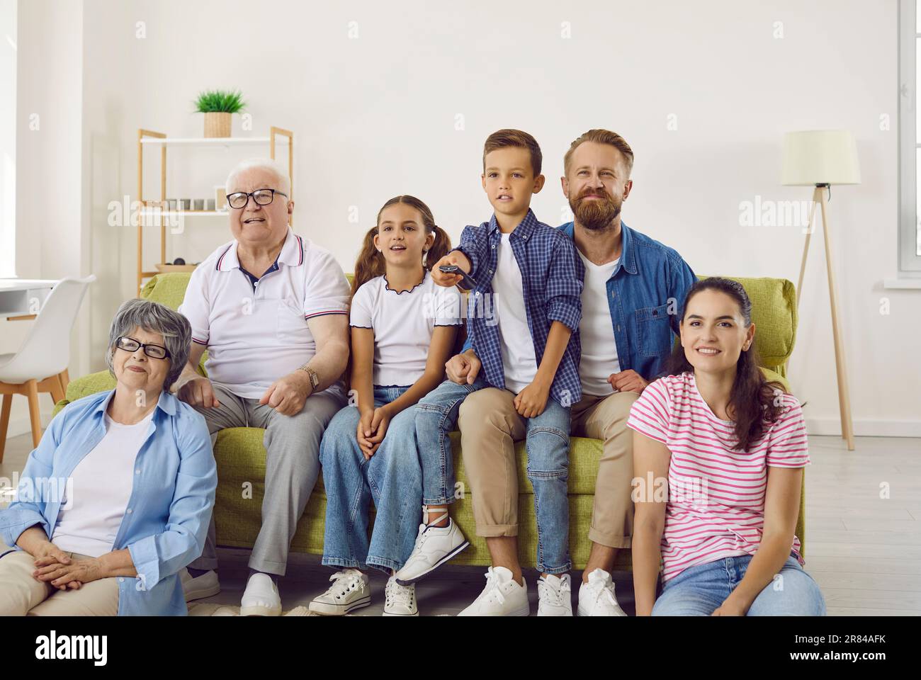 Cheerful multi-age big family watching TV together and enjoying spending time together. Stock Photo