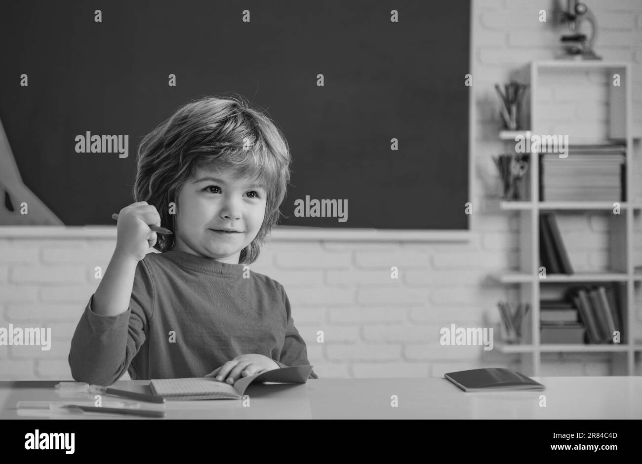 Children learning. Cute child boy in classroom near blackboard desk. Chalkboard copy space. School education and people concept - cute pupil over Stock Photo