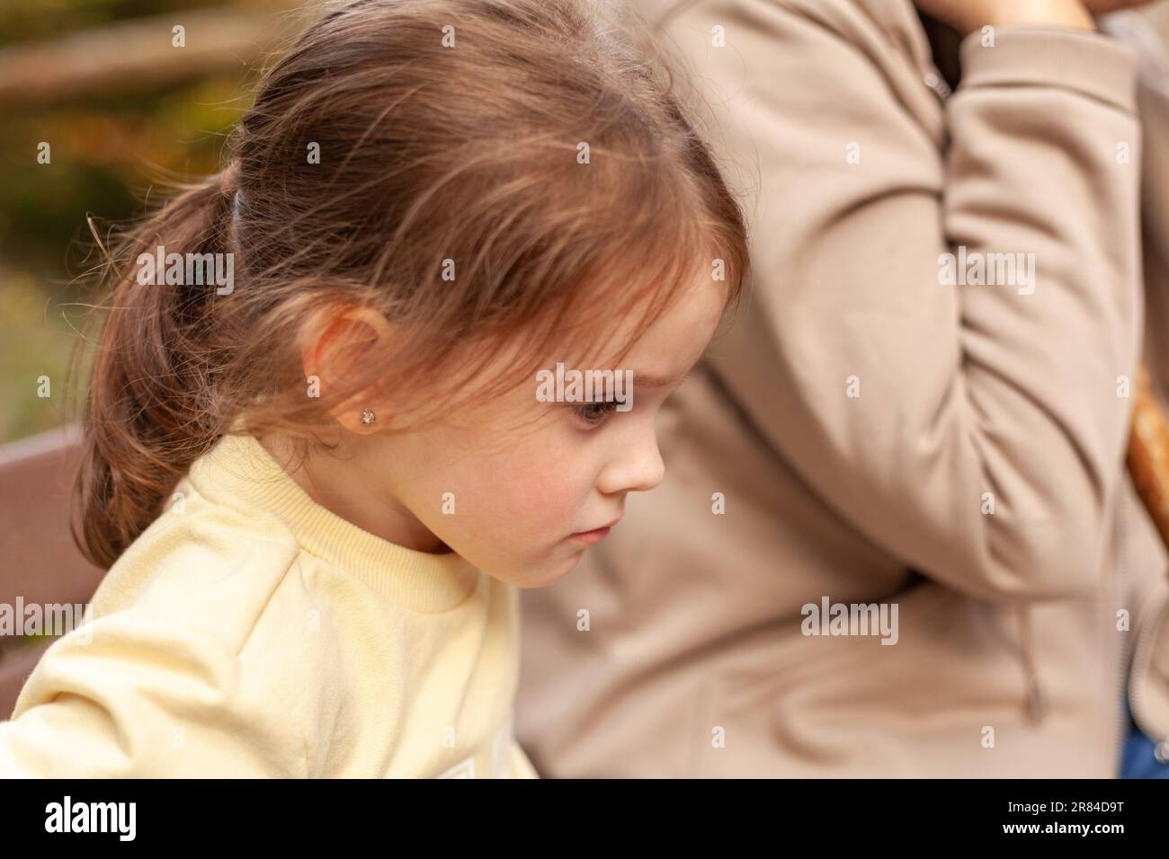 Little girl sitting on the bench with her mother in the park Stock ...