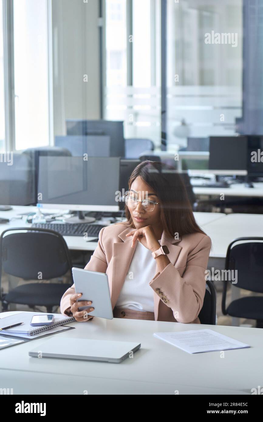 Young serious business woman manager using tablet in office thinking. Stock Photo