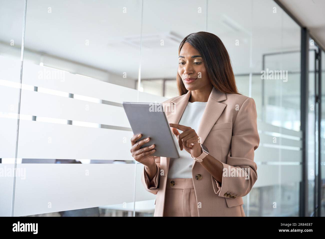 Young busy African American business woman using tablet standing in office. Stock Photo