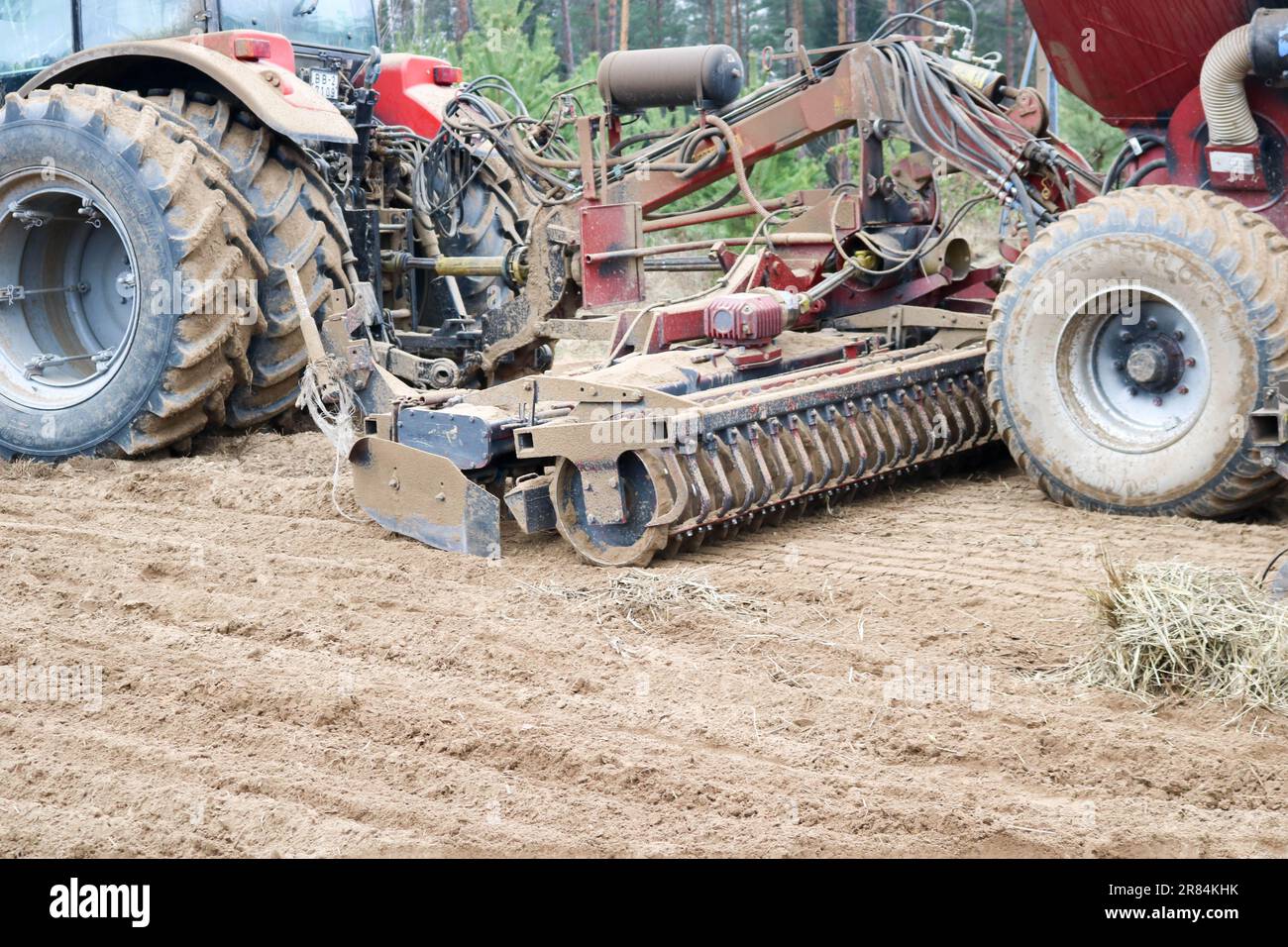 A tractor with a connected sowing unit, a combine, a drill with large  wheels plows the field, sows grain crops, performs agrarian, farm work on  the ba Stock Photo - Alamy