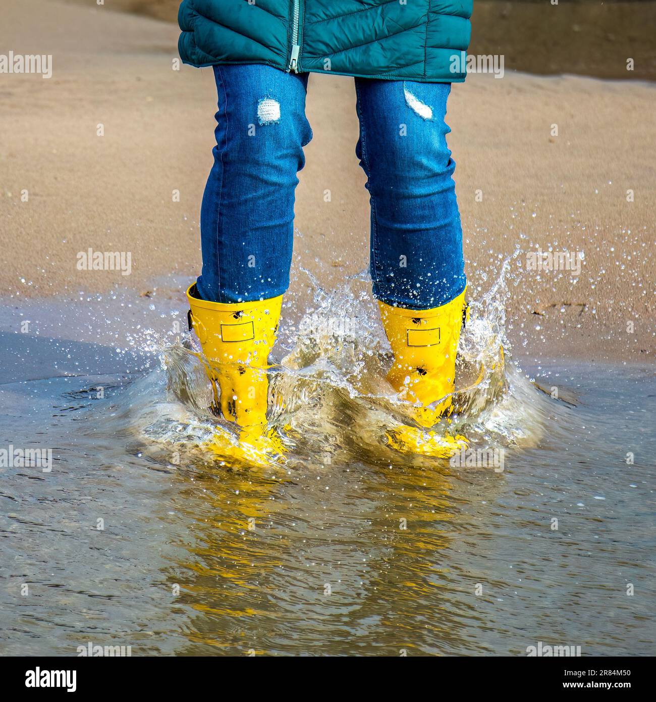 A girl in yellow rubber boots splashing water Stock Photo - Alamy