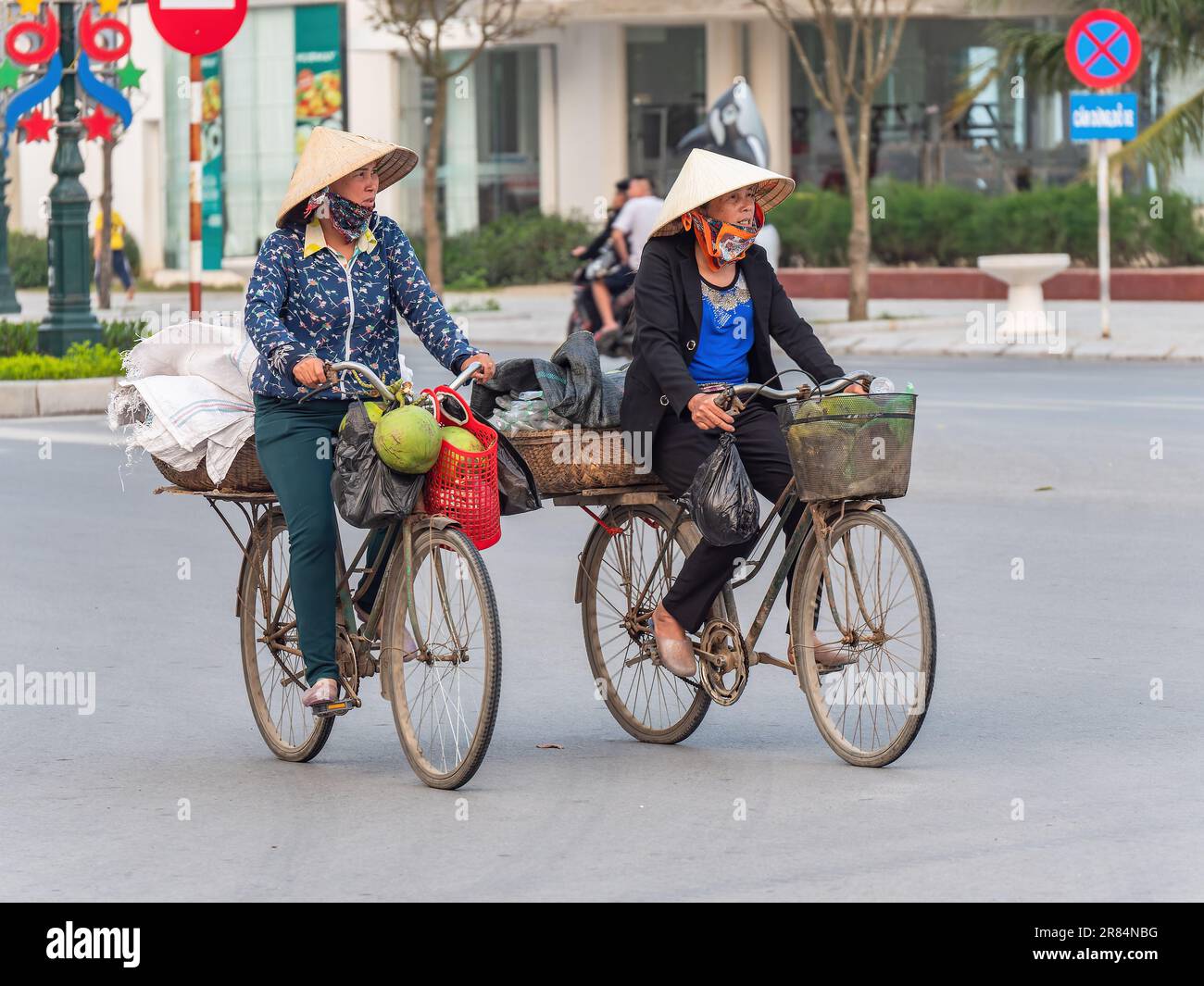 Two Vietnamese women on their bicycles at Sam Son Beach, Thanh Hoa, Vietnam Stock Photo