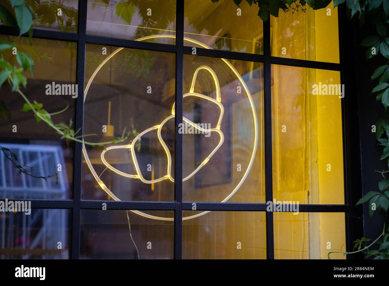 Croissant neon light sign hanging on café window. Stock Photo