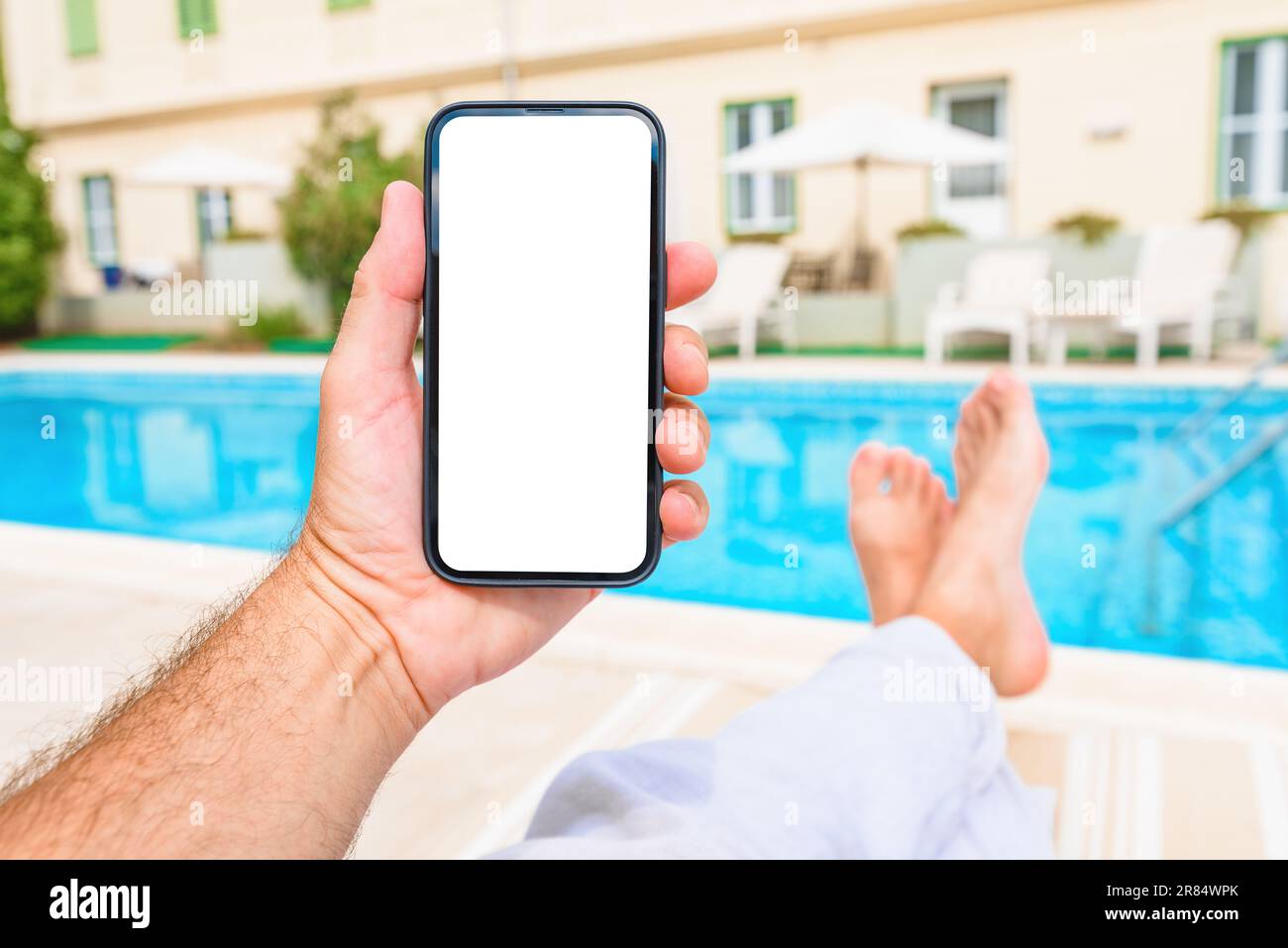 Man relaxing by the outdoor swimming pool with mockup smartphone in