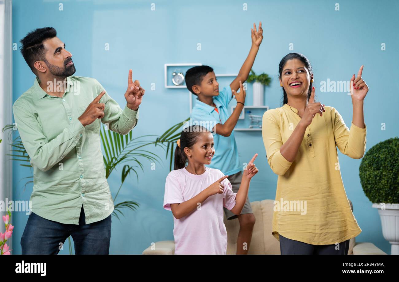 Cheerful Indian couple dancing with siblings kids at new home or apartment - concept of leisure activities, carefree living and holidays or vacation. Stock Photo