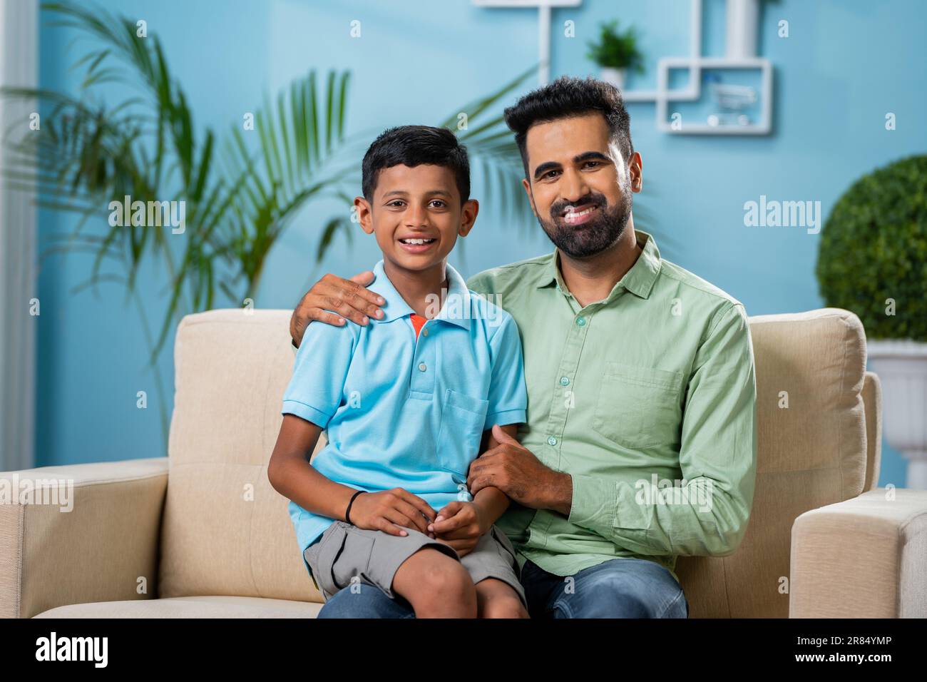 Happy Indian father with son looking at camera while talking eachother at home - conept of fatherhood, parenting and responsibility Stock Photo