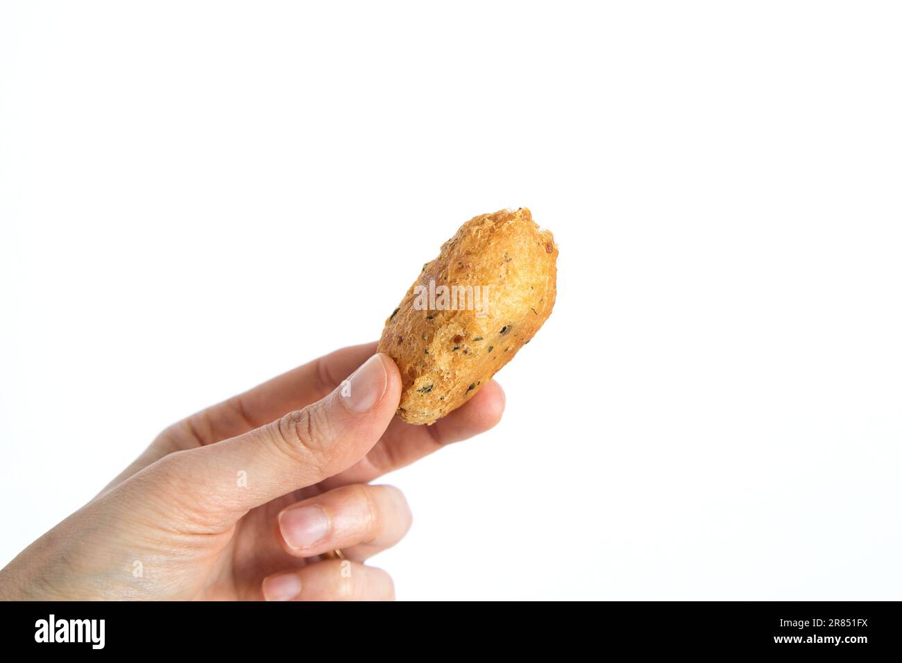Cod dumpling, or 'bolinho de bacalhau', very famous in Portuguese gastronomy. Fried dumpling, fish, salted cod fritters. Hand holding cod fritter. Stock Photo