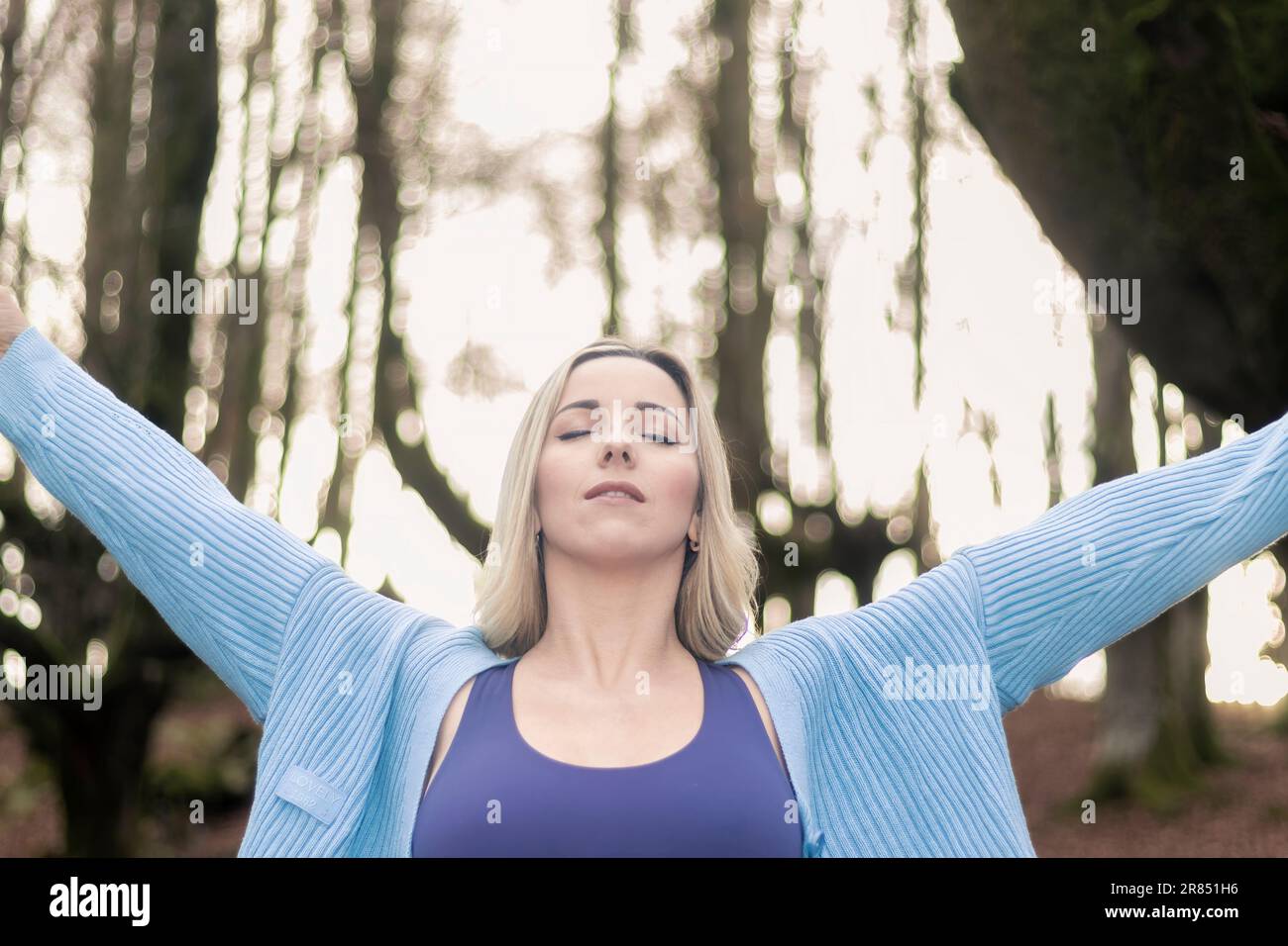 Forest Renewal: Blonde Woman Embracing Inner Peace Through Deep Breathing in Nature Stock Photo