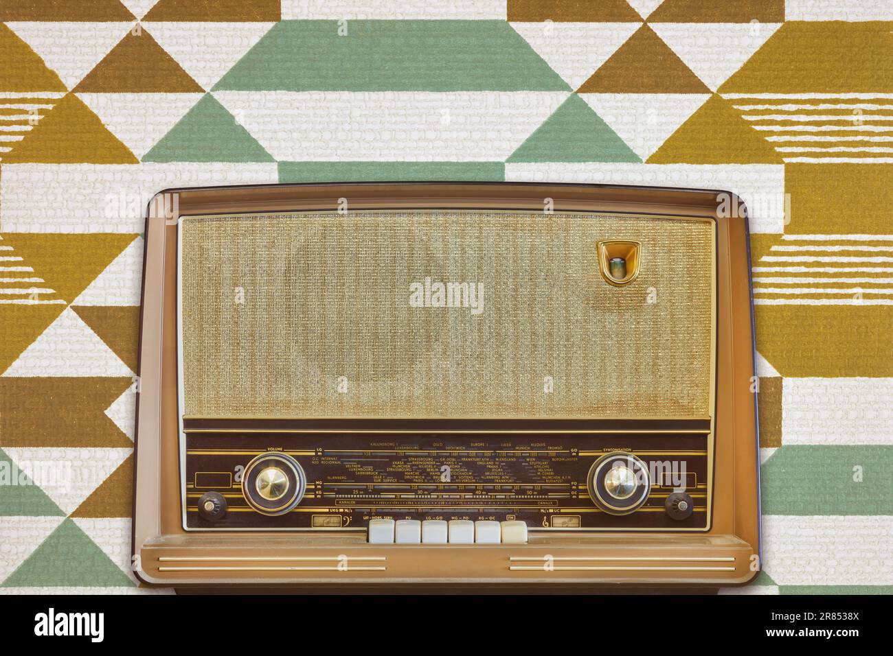Vintage radio with display showing European cities in front of retro wallpaper Stock Photo