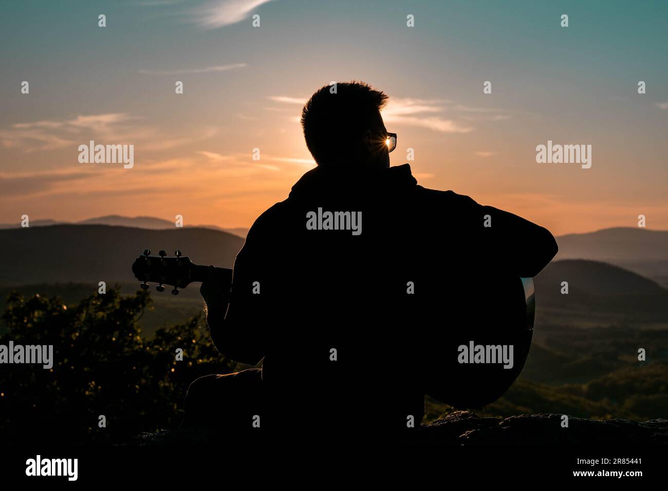 Man with guitar silhouette with mountain view in Slovak landside in beautiful sunset Stock Photo