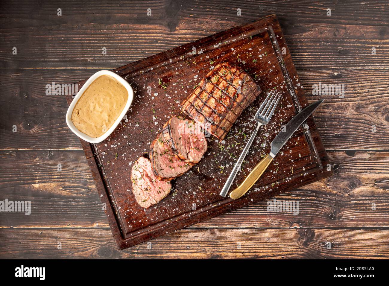 Sliced grilled beef tenderloin seasoned with salt, rosemary and thyme on a wooden cutting board Stock Photo