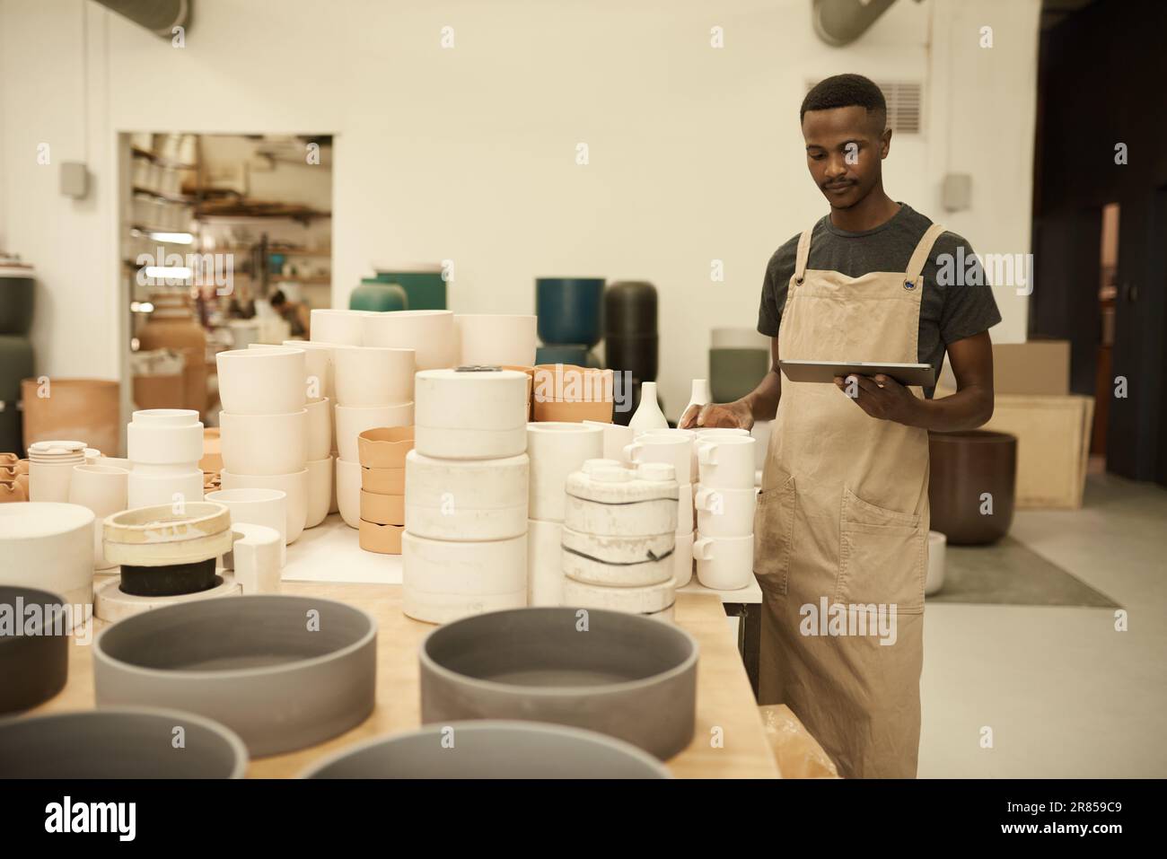 African potter doing inventory using a tablet in a ceramics workshop Stock Photo
