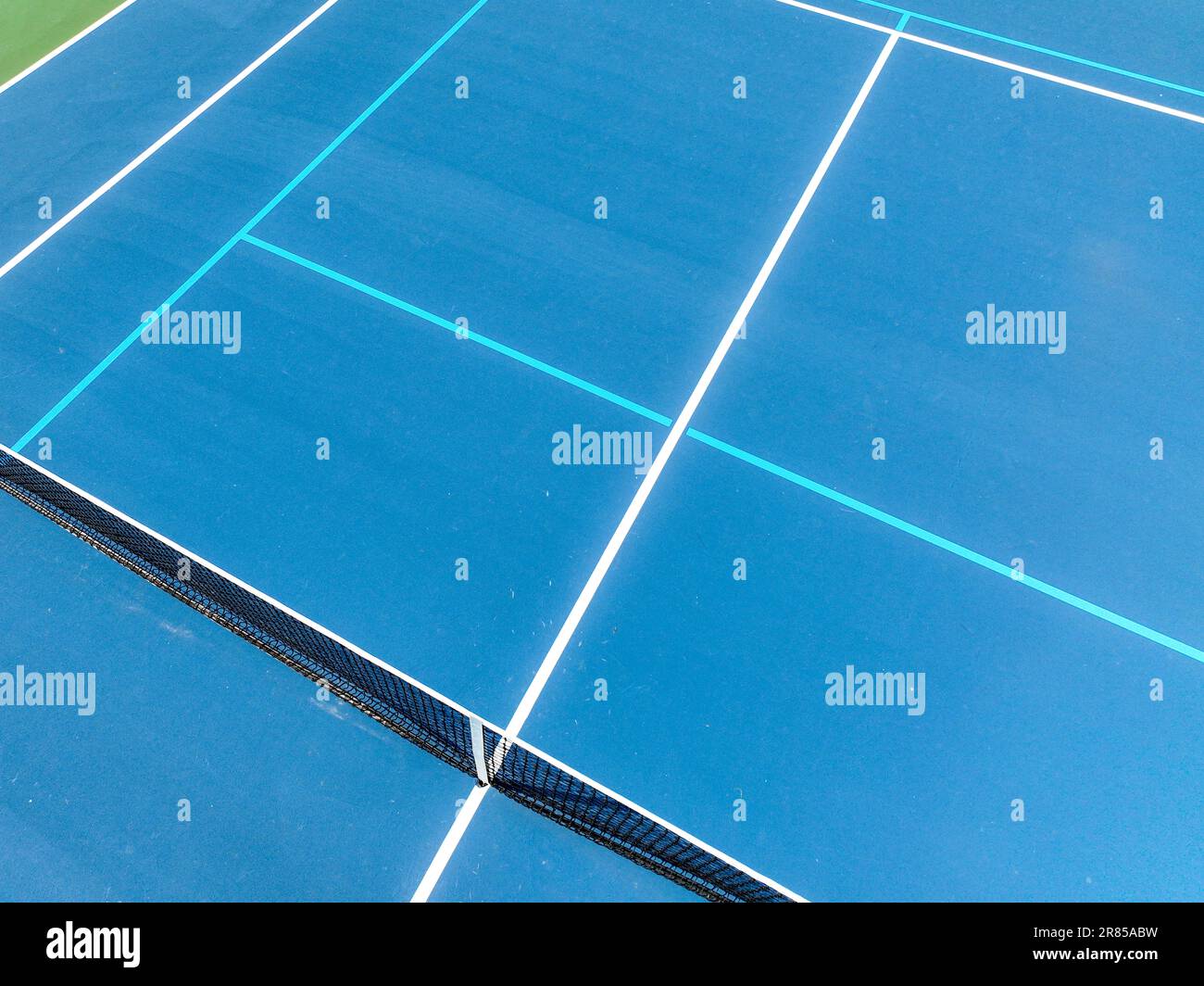 Aerial photo of blue tennis courts with white lines and light blue