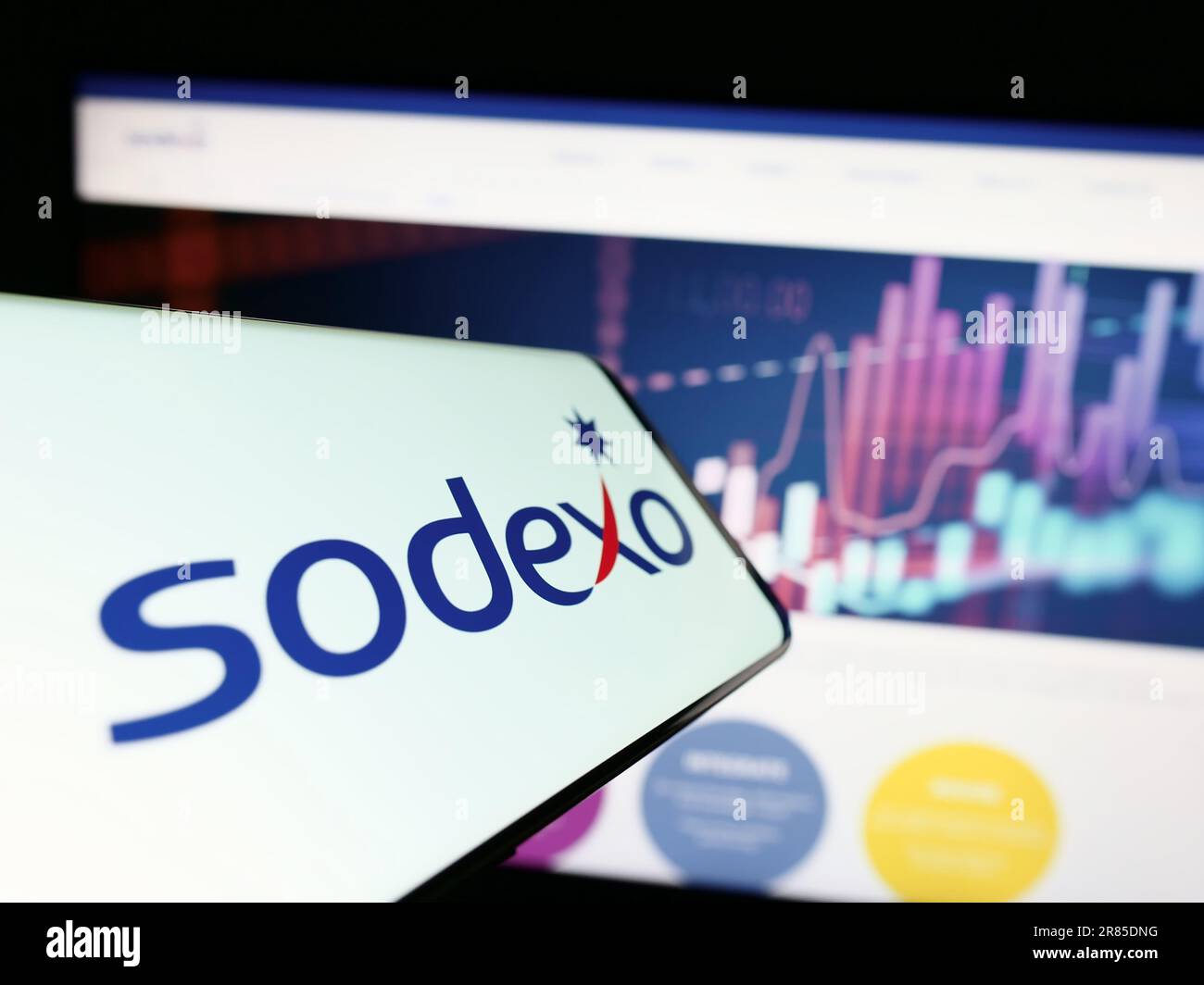 Cellphone with logo of French facility management company Sodexo S.A. on screen in front of website. Focus on center-right of phone display. Stock Photo