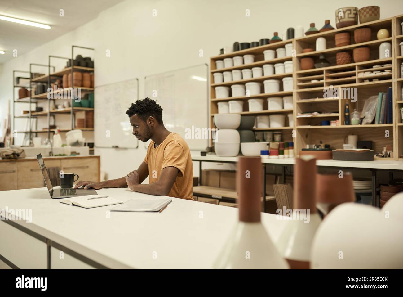 African ceramics workshop manager using on a laptop at a table Stock Photo