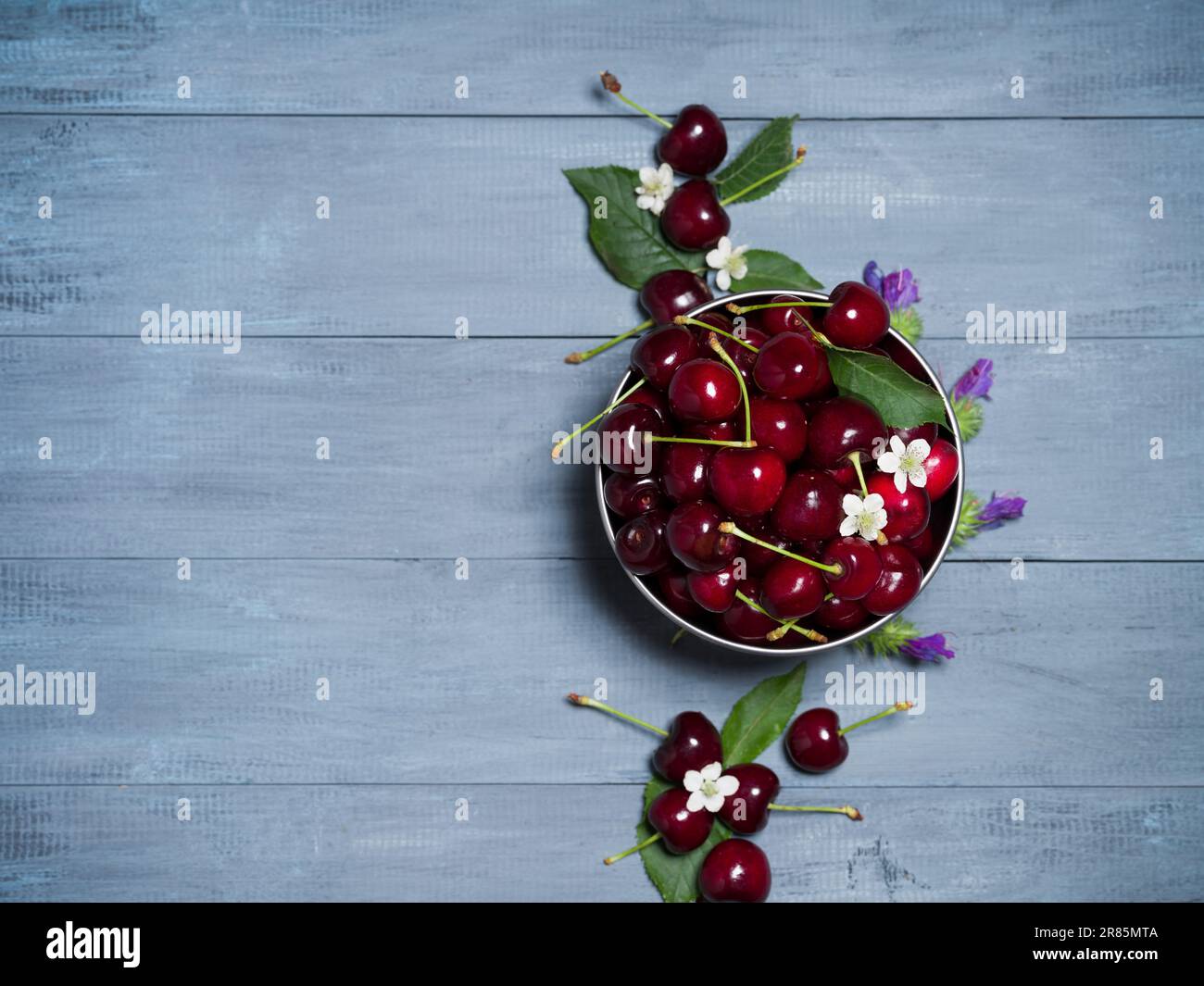 Fresh cherries in a bowl on rustic textured table. Red summer fruits concept Stock Photo