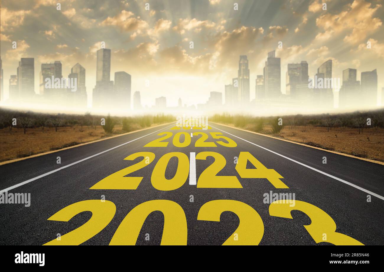 The word 2024 to 2028 written on highway road in the middle of empty asphalt road at golden sunrise. New year 2024 concept. Concept of planning Stock Photo