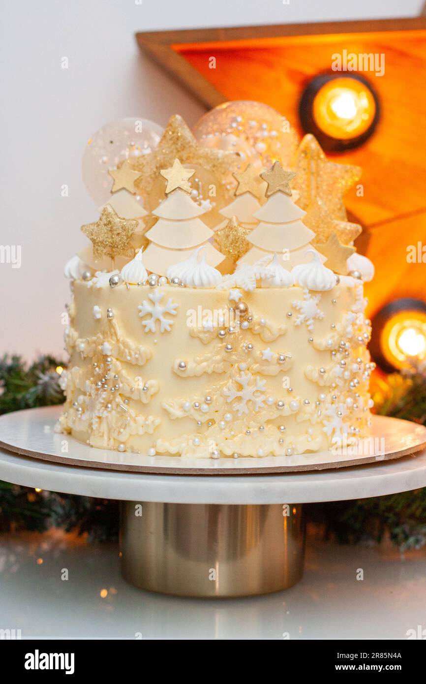 Festive golden and white christmas cake with creamy christmas trees, lollipops, fondant