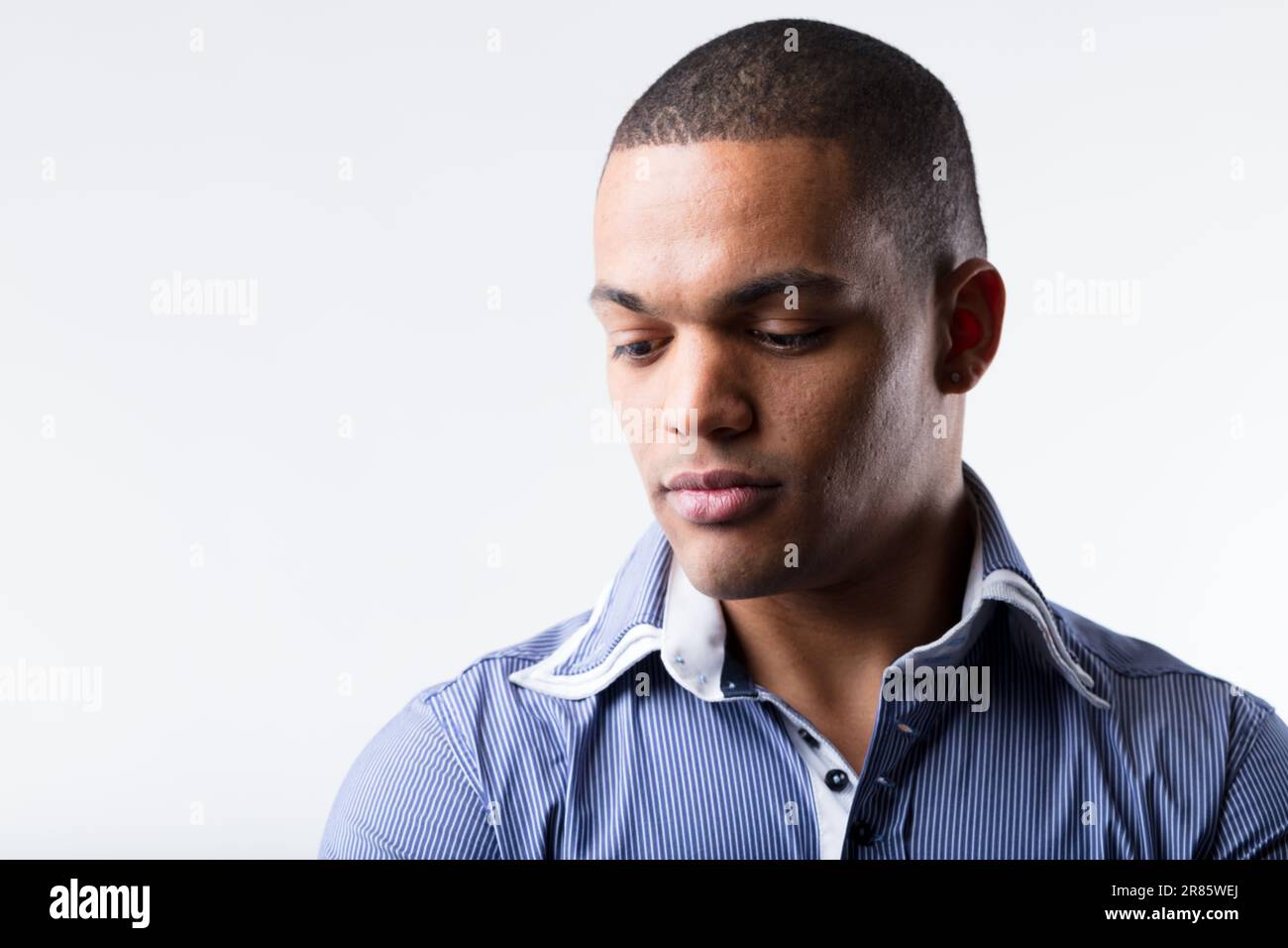 A well-off black man, part of high-earning middle class, wears a blue polo-style shirt. He appears thoughtful and perhaps worried, troubled, sad, seri Stock Photo
